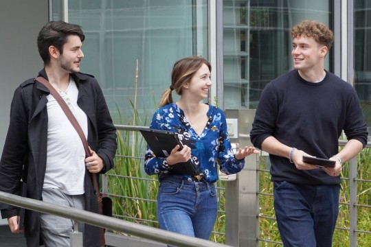 Drei Auszubildende im Gespräch beim Gang über den Innenhof eines LVR-Gebäudes