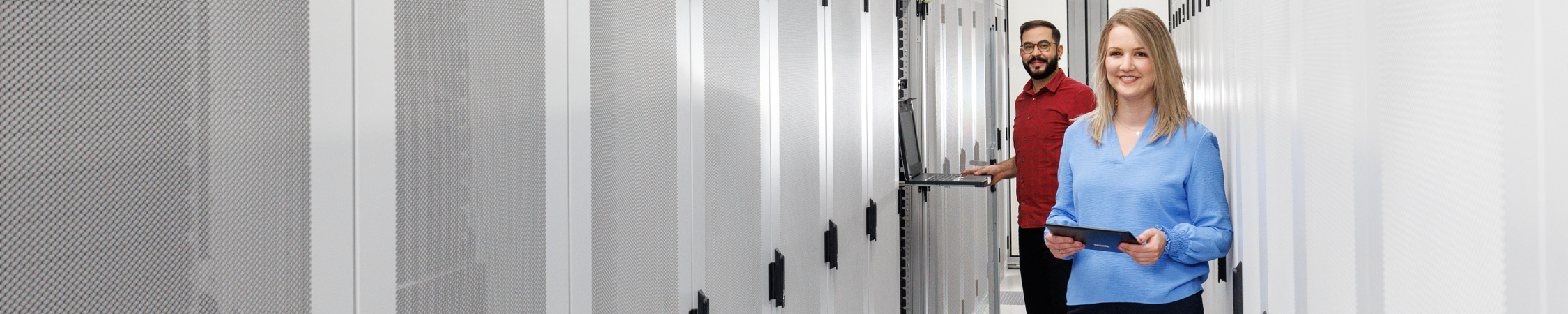 Ein Mann und eine Frau stehen vor Serverschränken