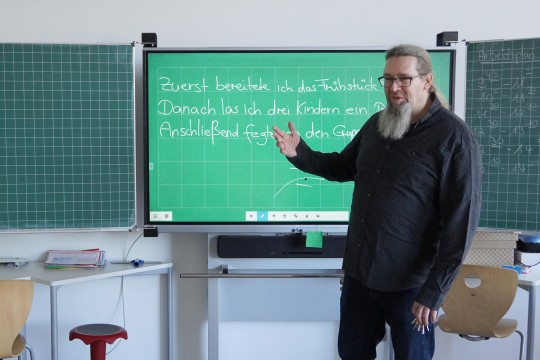 Ein Lehrer steht vor einem digitalen Tafelsystem